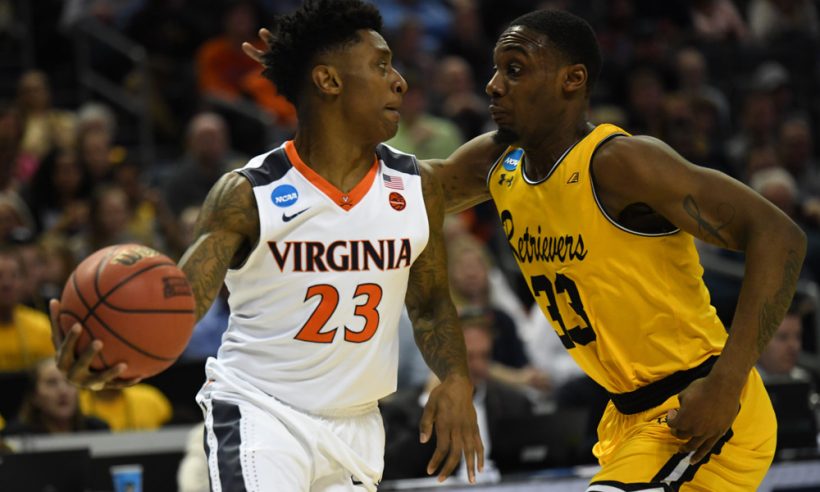 Virginia Cavaliers guard Nigel Johnson (23) is guarded tightly by UMBC Retrievers forward Arkel Lamar (33) during the NCAA Division I Men's Championship First Round game between the UMBC Retrievers and the Virginia Cavaliers on March 16, 2018 at the Spectrum Center in Charlotte, NC.